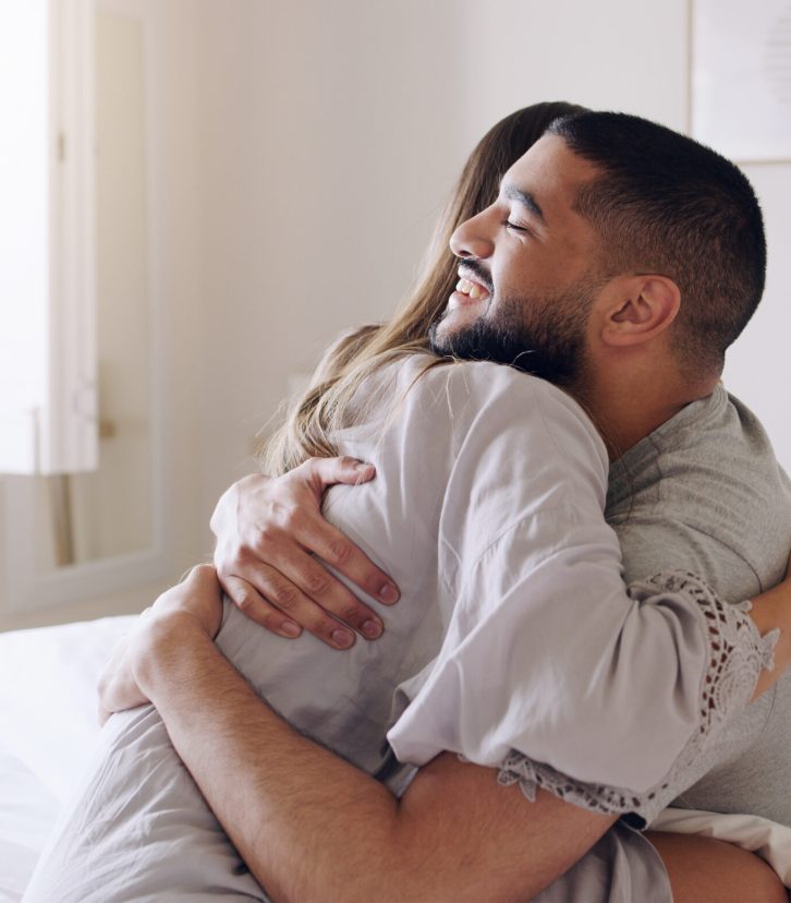Couple, hug and happy for pregnancy test in bedroom, home and support to celebrate good news. Excited man, woman and partner hugging in celebration of pregnant results, future family or ivf fertility Couple, hug and happy for pregnancy test in bedroom, home and support to celebrate good news. Excited man, woman and partner hugging in celebration of pregnant results, future family or ivf fertility.