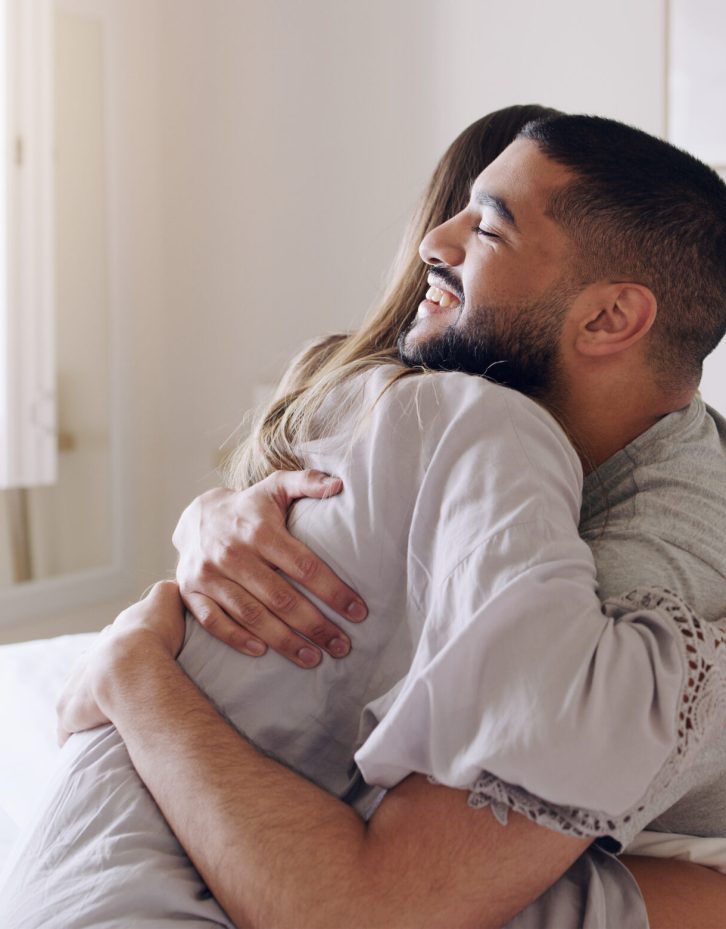 Couple, hug and happy for pregnancy test in bedroom, home and support to celebrate good news. Excited man, woman and partner hugging in celebration of pregnant results, future family or ivf fertility Couple, hug and happy for pregnancy test in bedroom, home and support to celebrate good news. Excited man, woman and partner hugging in celebration of pregnant results, future family or ivf fertility.